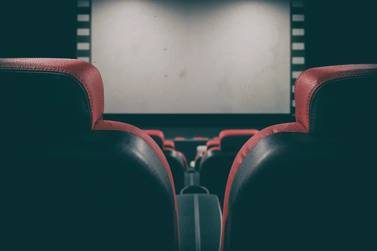 Red and black cinema seats facing a blank movie screen