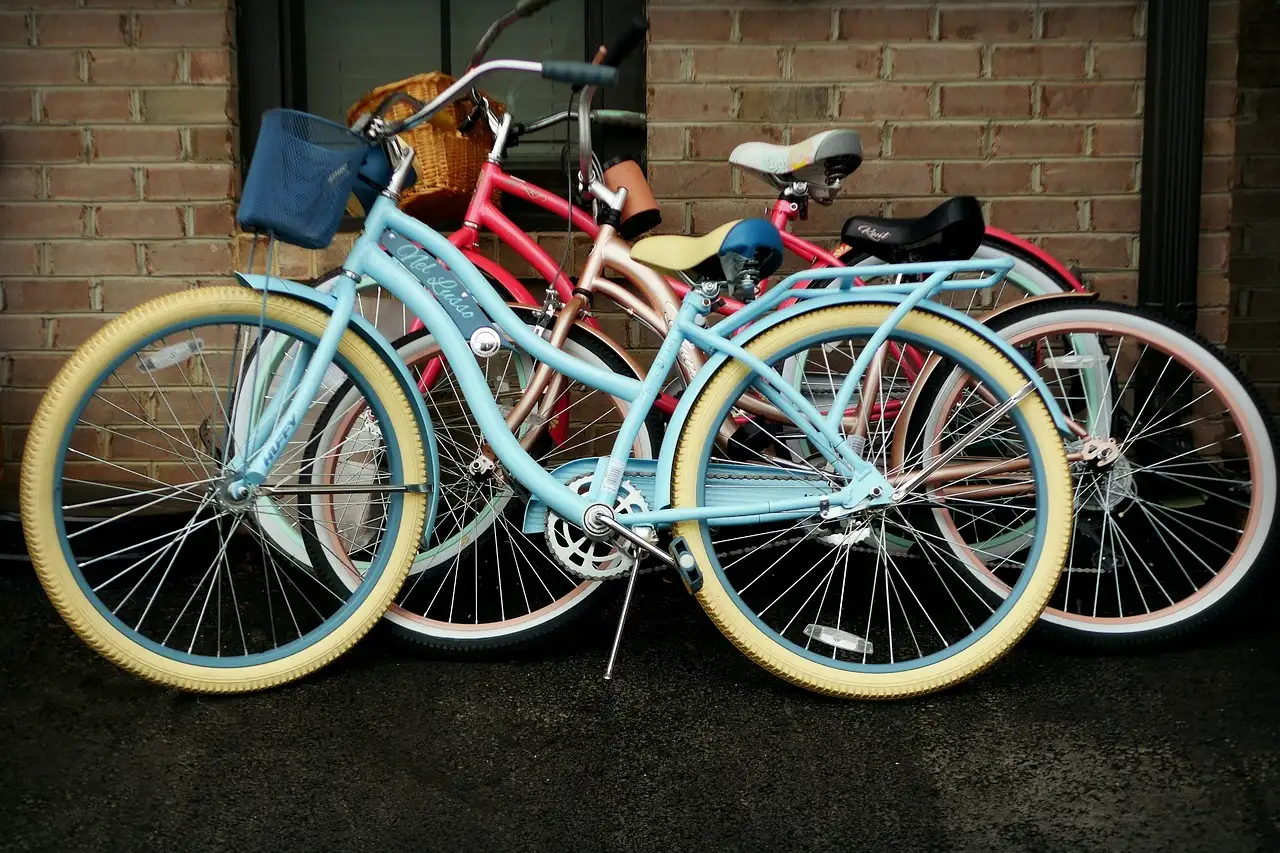 Three colourful beach cruiser bikes parked against a brick wall
