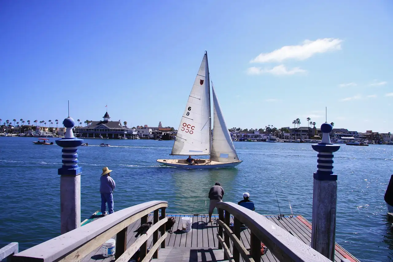 A sailboat on the bay off Balboa Island, seen from a dock