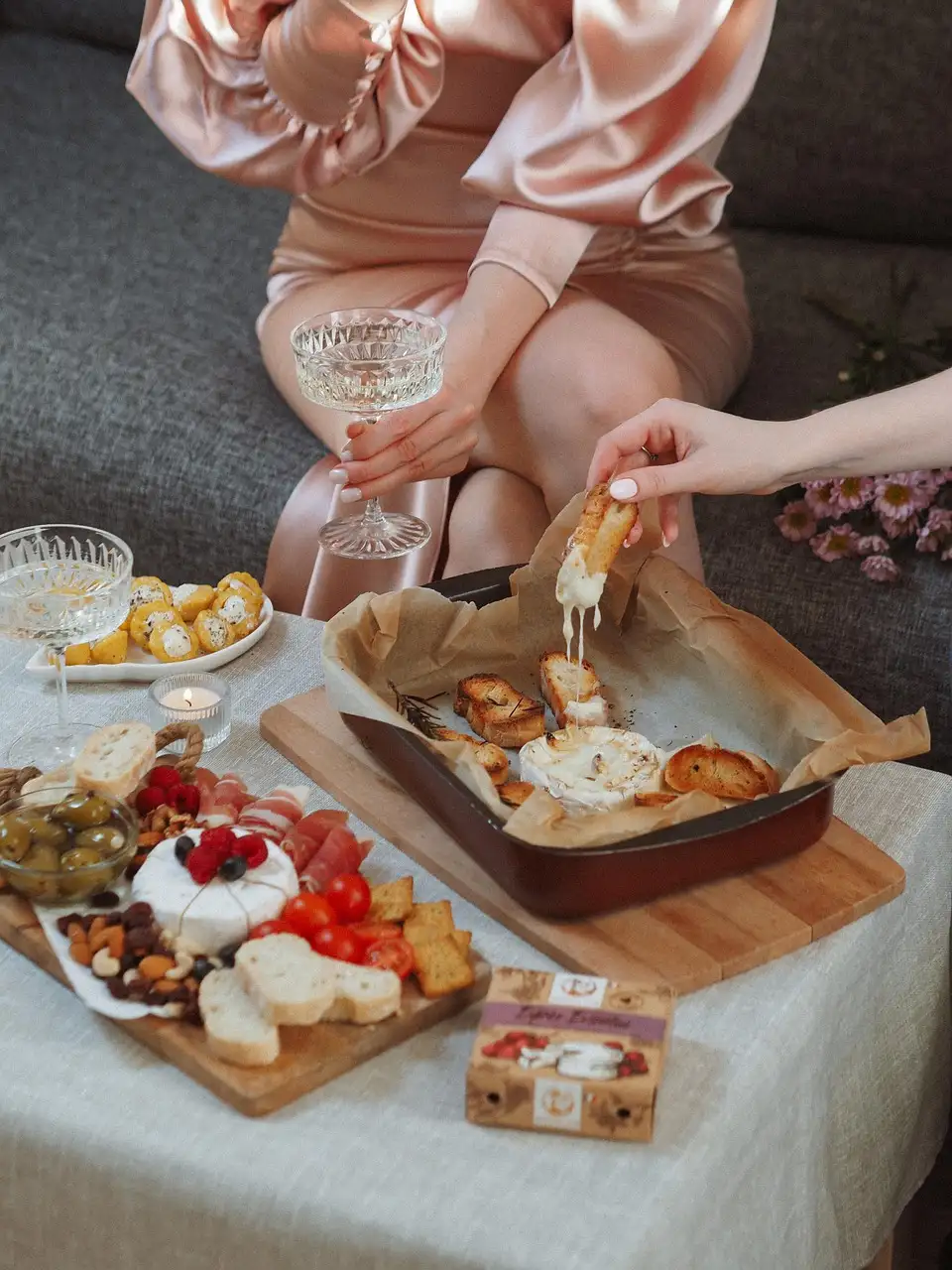 A charcuterie board with cheese and fruit next to a glass of wine