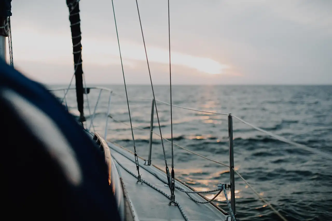 The deck and rigging of a sailboat at sea at sunset