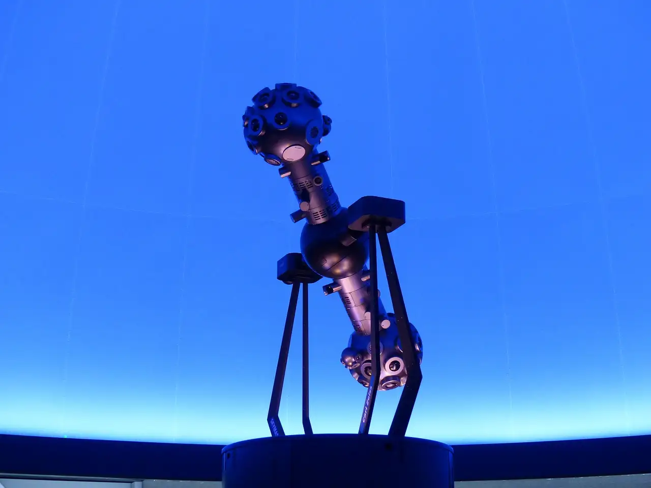 A star projector under a glowing blue dome screen