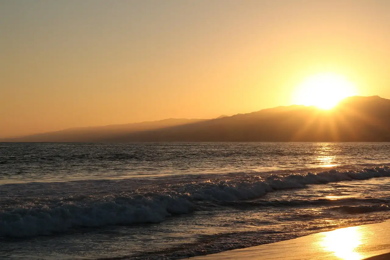 Sun setting over the Santa Monica Mountains and the waves of Santa Monica Bay
