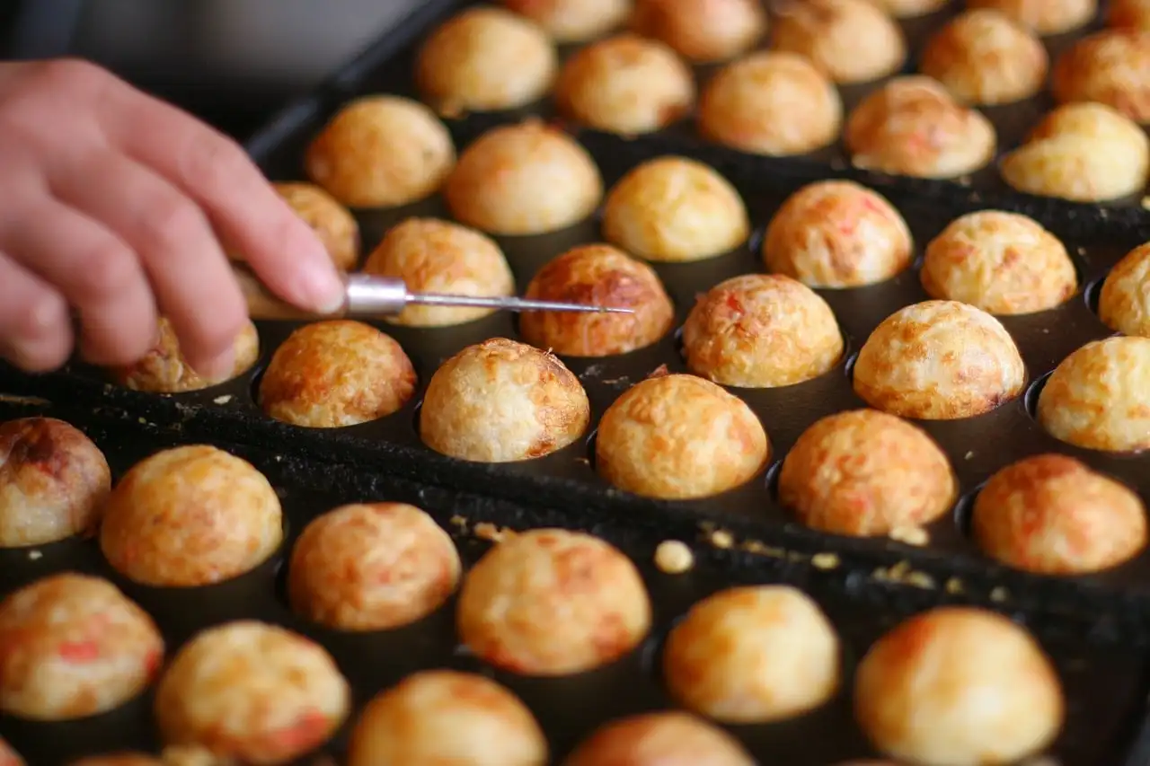 Takoyaki balls cooking in a round-holed pan