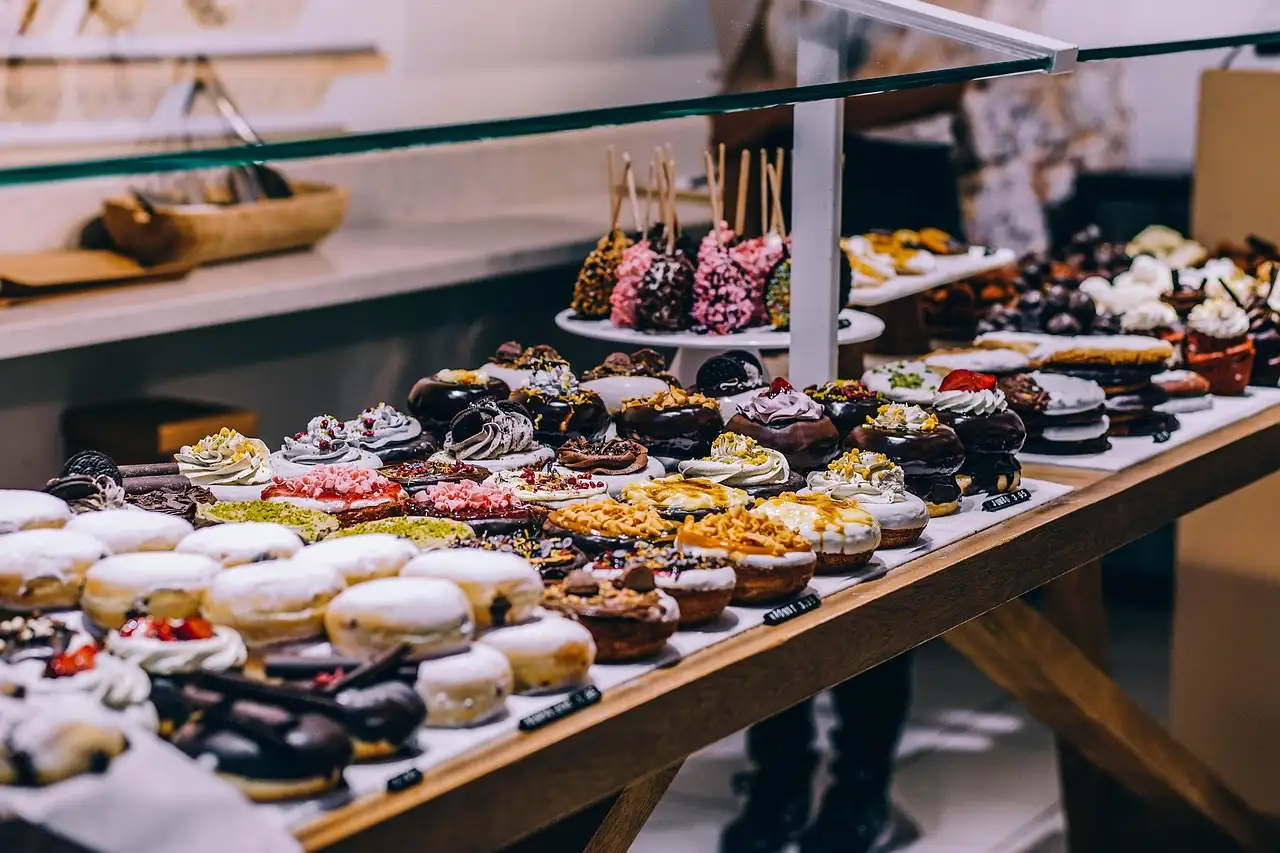 Rows of glazed and frosted doughnuts on a shop counter
