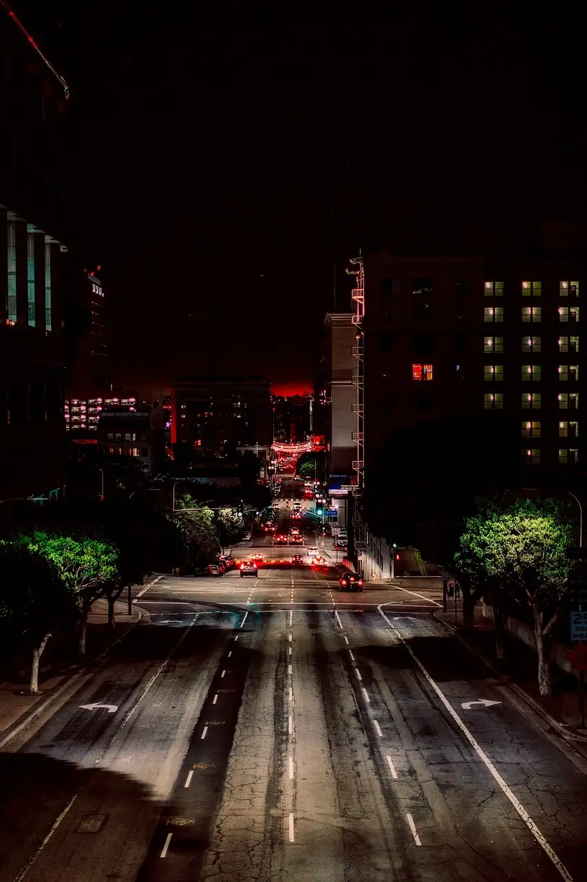 A street in Downtown Los Angeles at night with red lights and tall buildings
