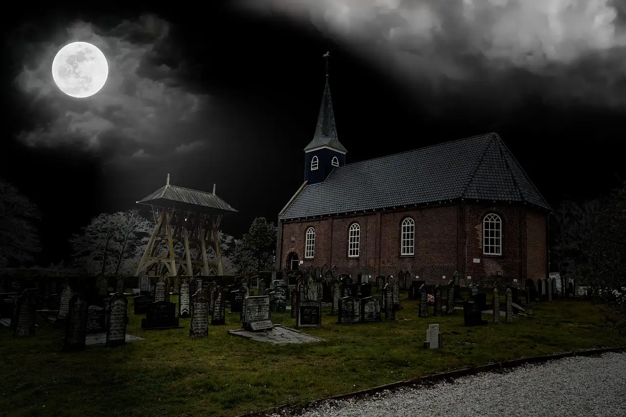 A full moon over an old church and graveyard at night