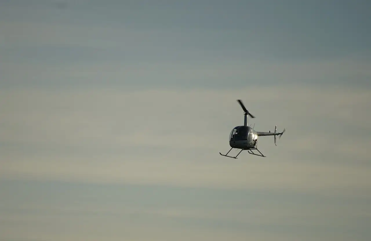 A small helicopter flying in a hazy grey sky
