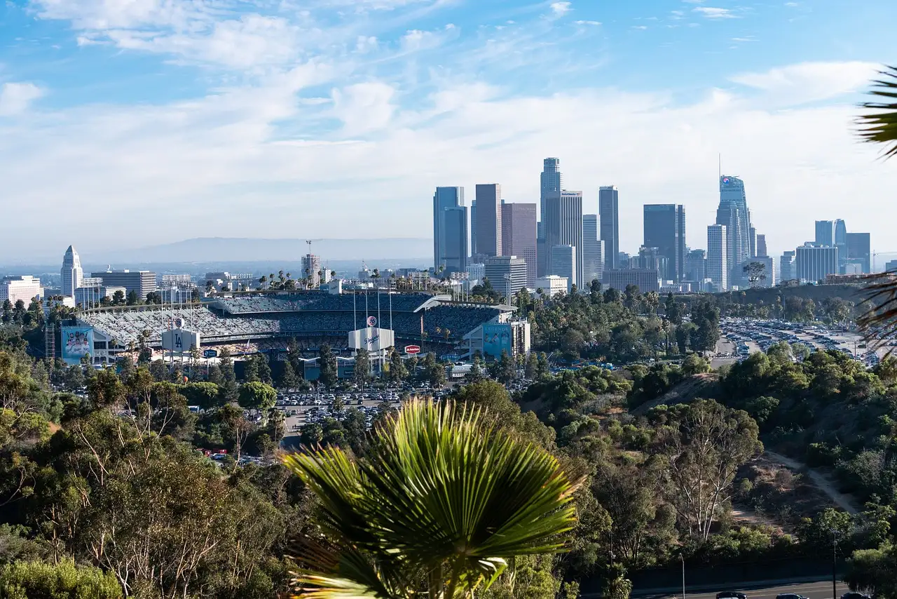 The skyline of Downtown Los Angeles seen over green hills and palm trees