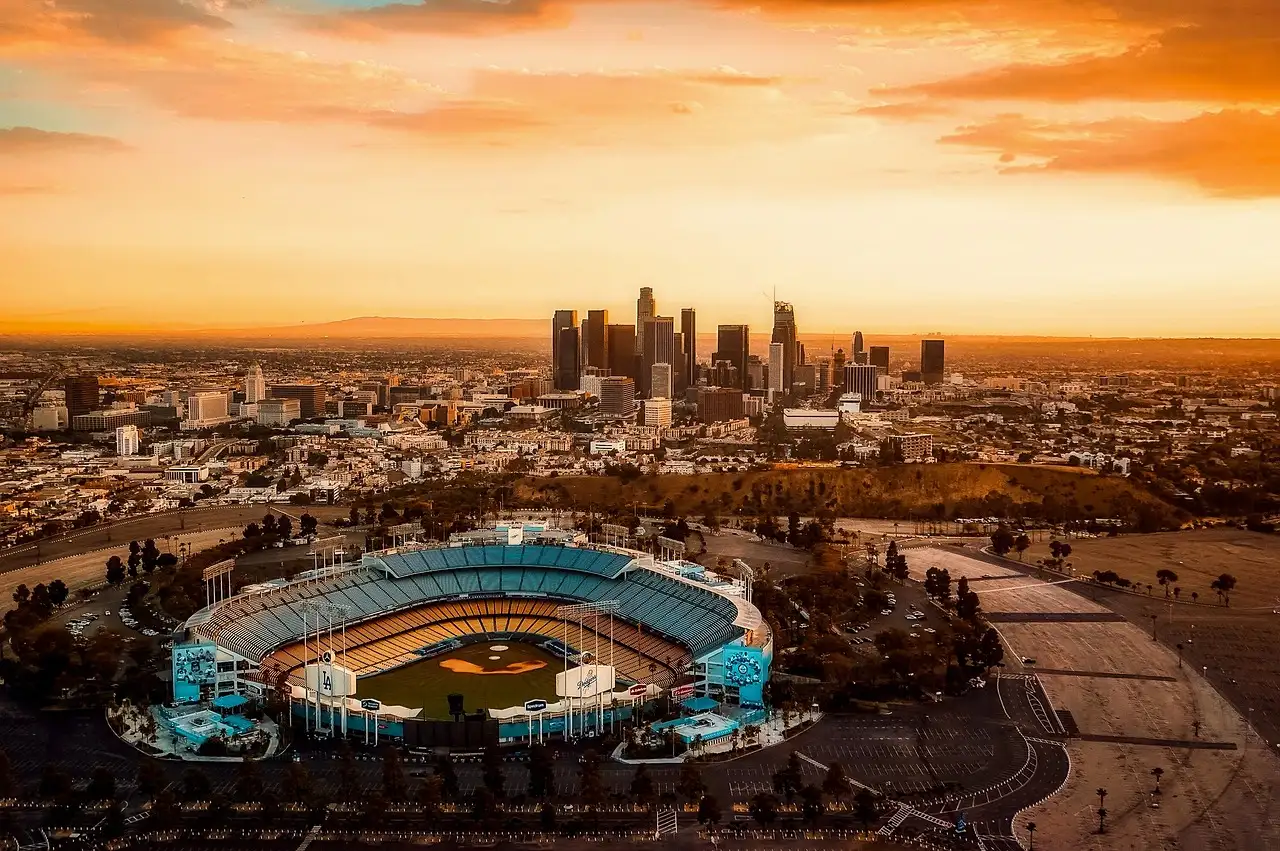 Dodger Stadium from above at sunset, with the Downtown Los Angeles skyline behind it
