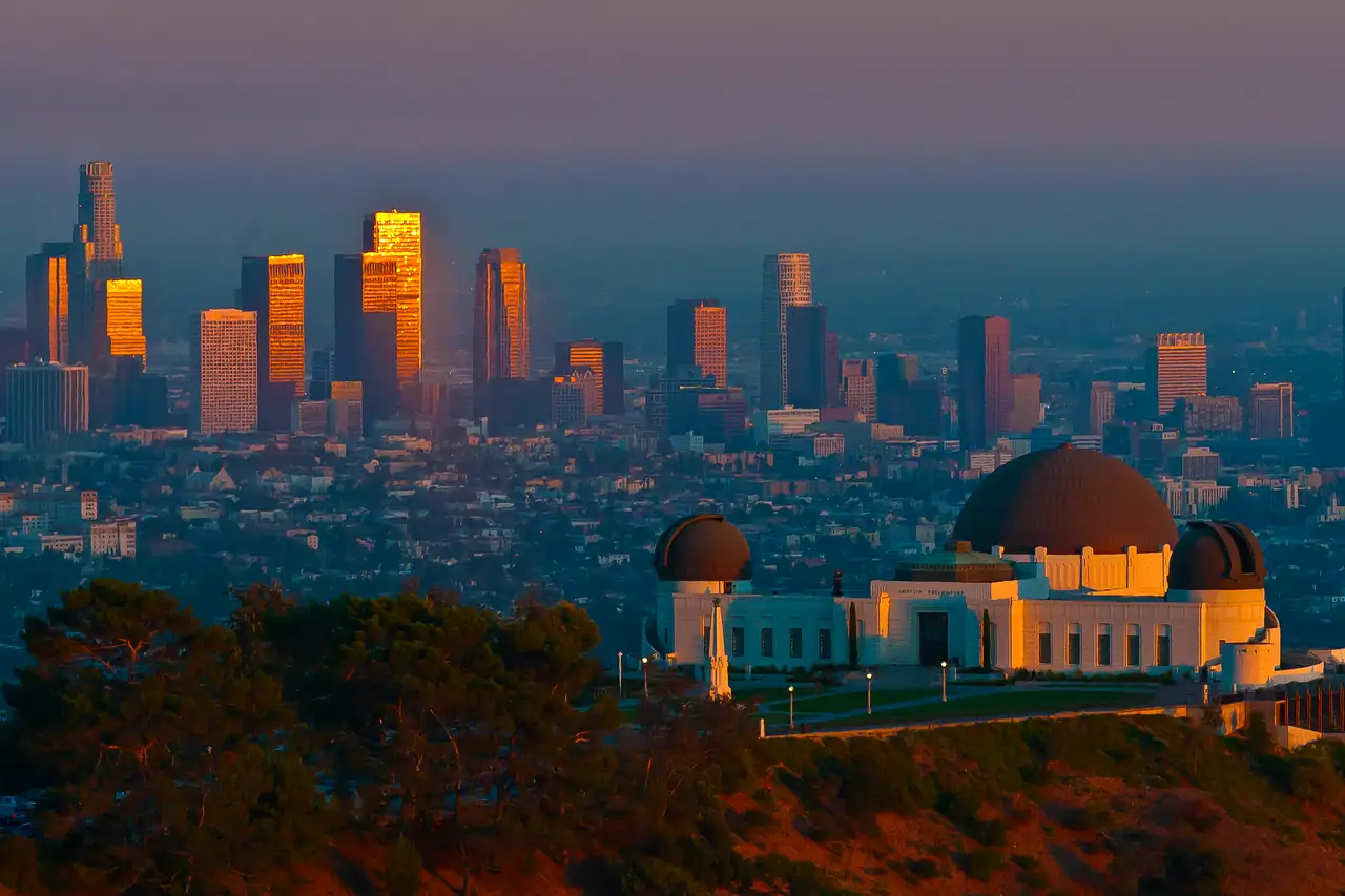 Griffith Observatory at sunset with the downtown Los Angeles towers behind it