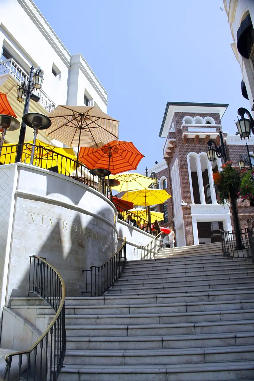 A narrow stairway between white buildings with colourful umbrellas off Rodeo Drive