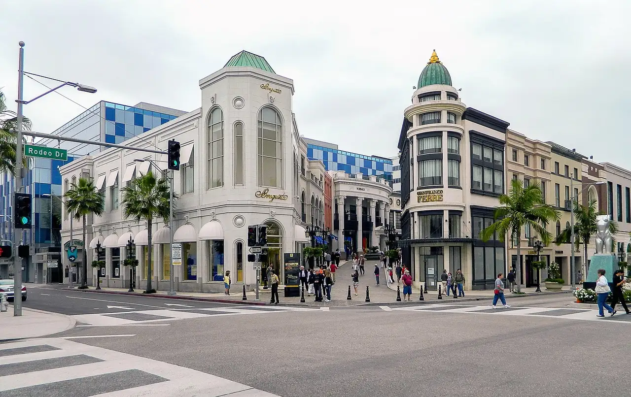 Shoppers crossing the street between white boutique buildings on Rodeo Drive