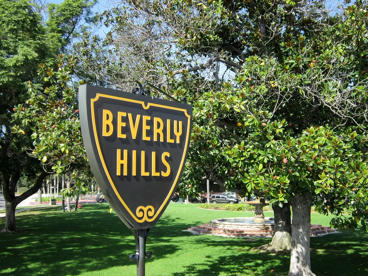 The shield-shaped Beverly Hills sign in a green park with trees
