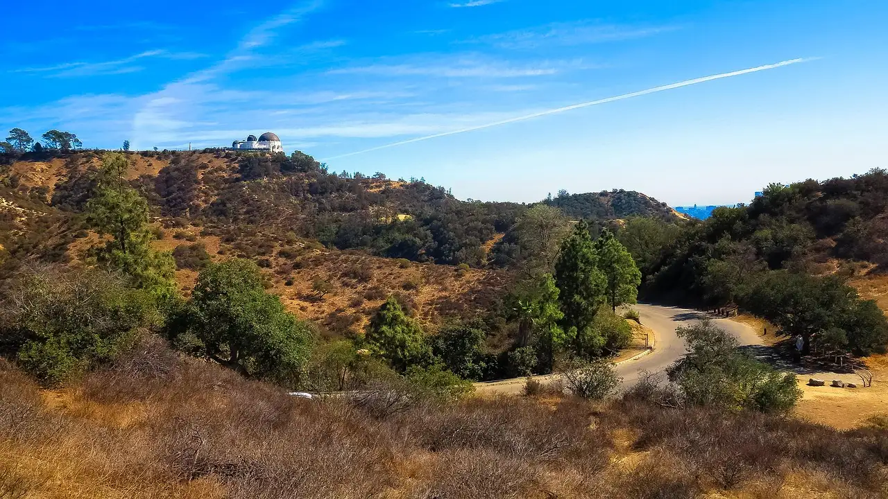 Dry hills and a dirt path in Griffith Park, with the observatory far away on a ridge