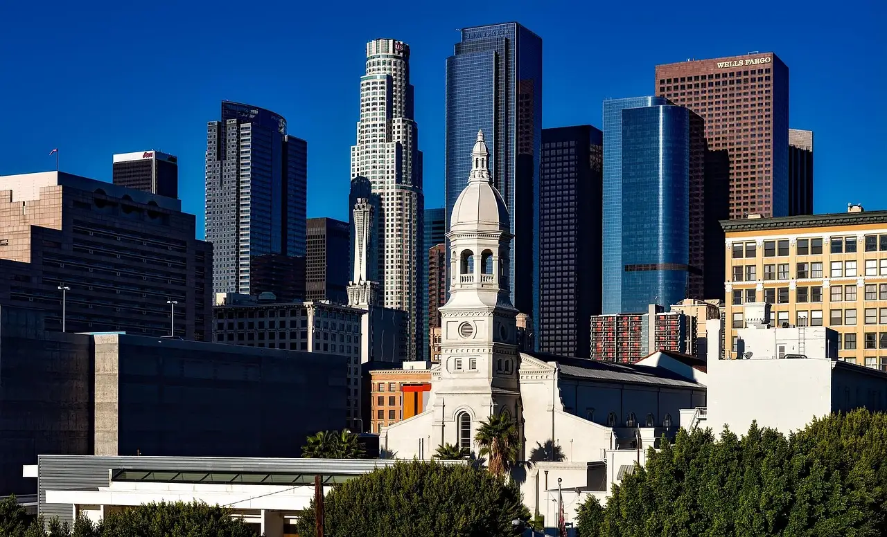 Downtown Los Angeles skyscrapers behind a white church tower on a clear day
