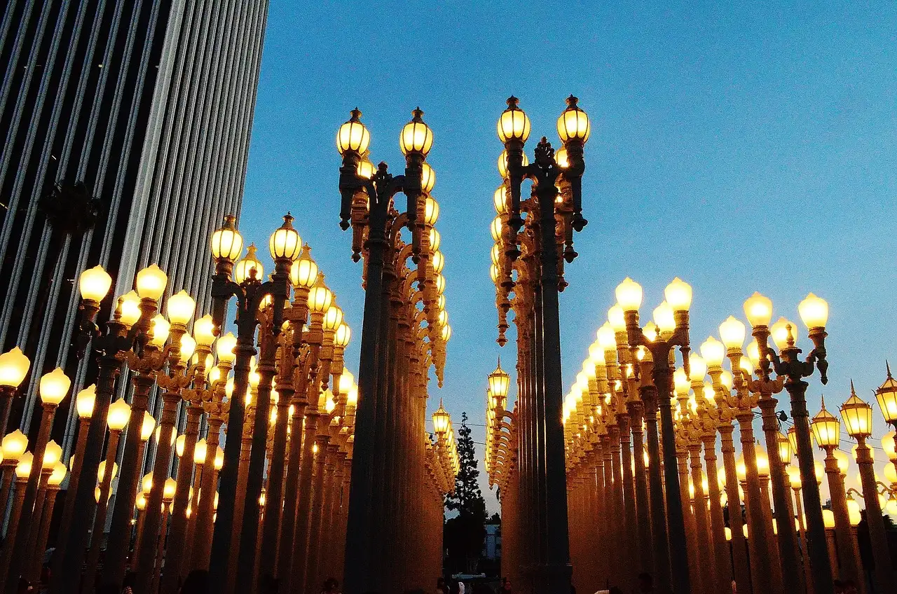 Rows of lit vintage street lamps of the Urban Light sculpture at LACMA at dusk