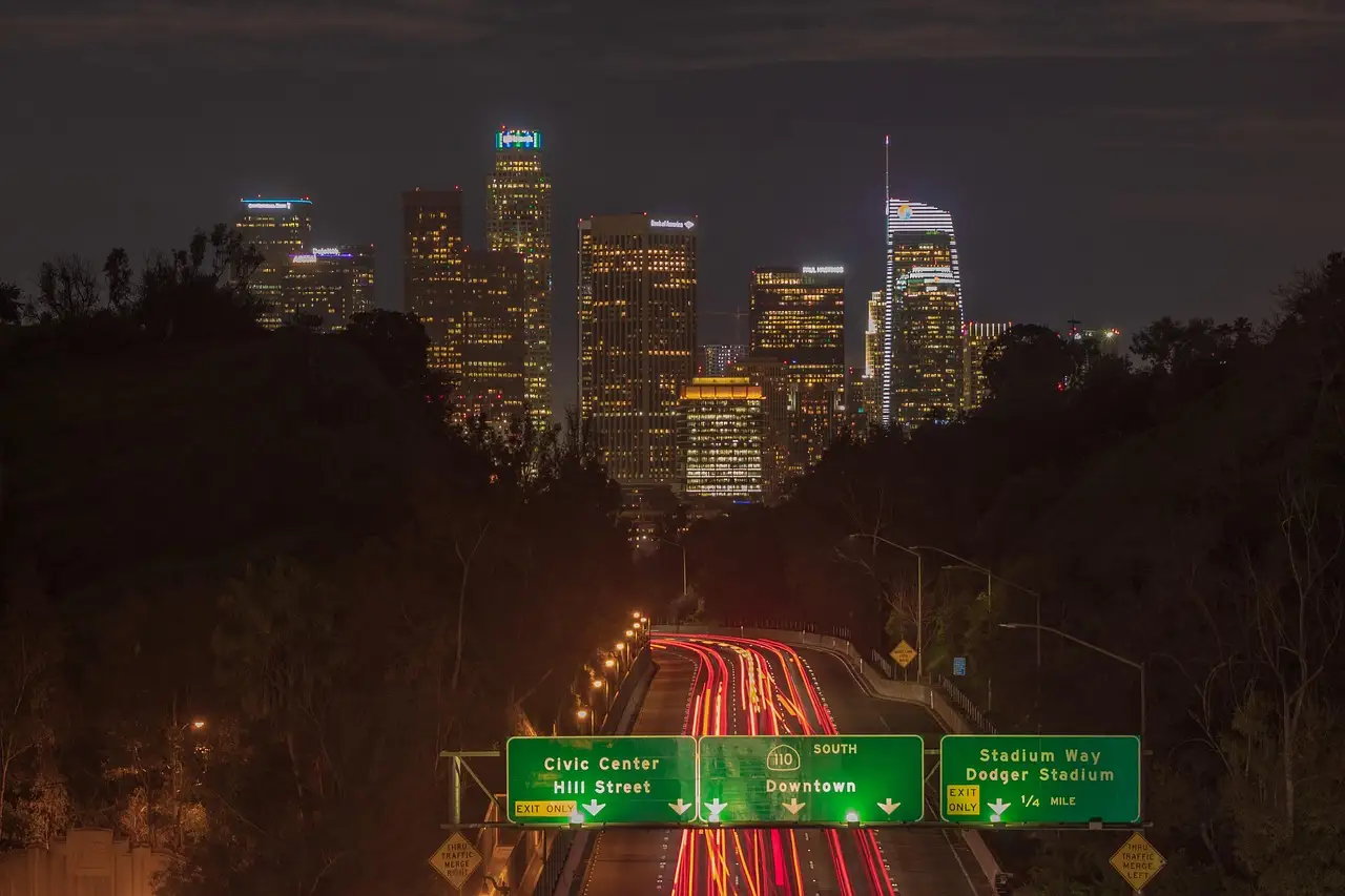 Downtown Los Angeles skyline at night with light trails on the freeway below