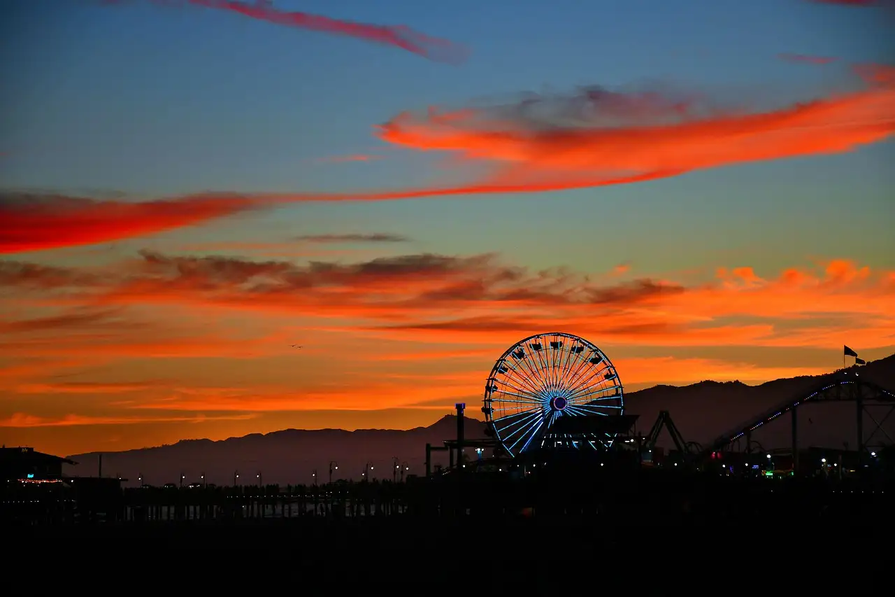 The Santa Monica Pier Ferris wheel in silhouette against a red sunset