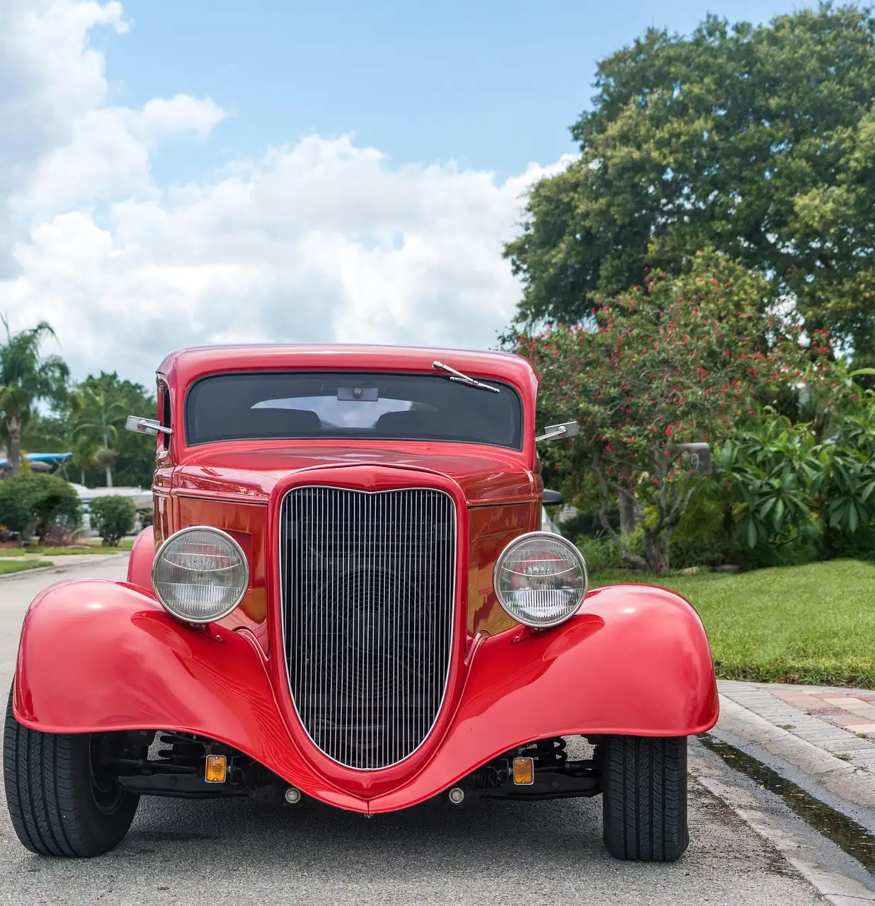 Front view of a red hot rod parked on a sunny street