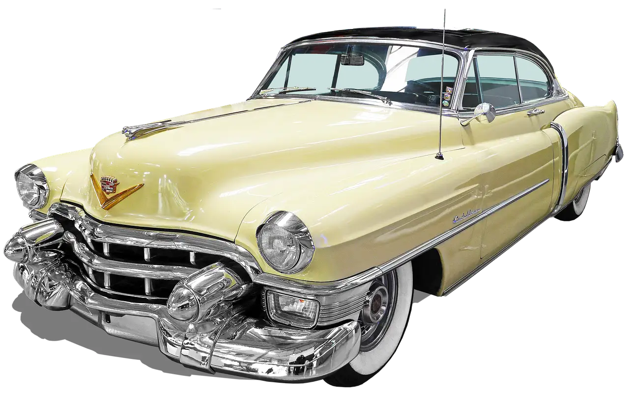 A cream-colored 1950s American car with chrome bumpers and whitewall tires