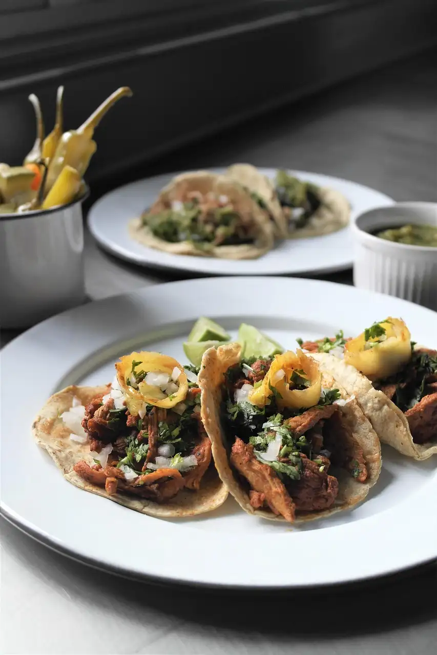 Three tacos al pastor with onion and coriander on a plate