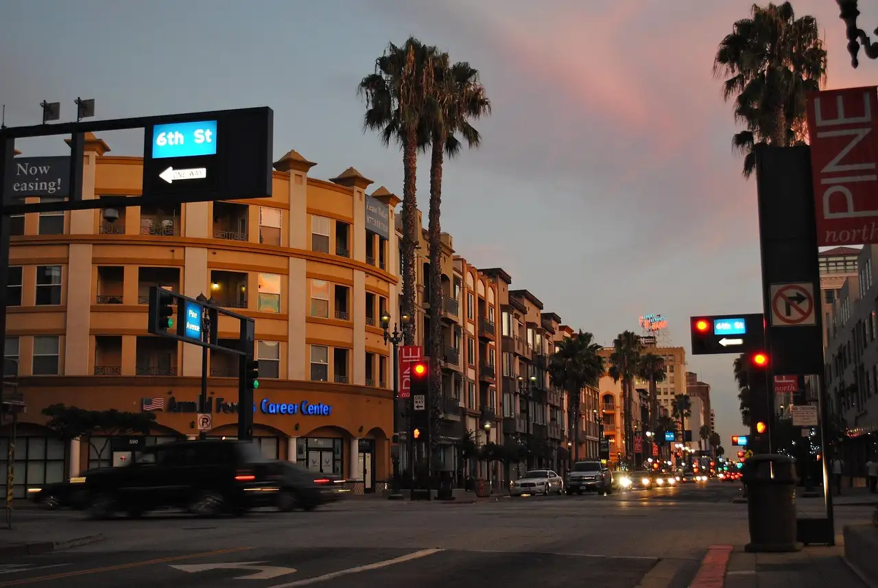 A downtown Long Beach street with palm trees and traffic lights at dusk