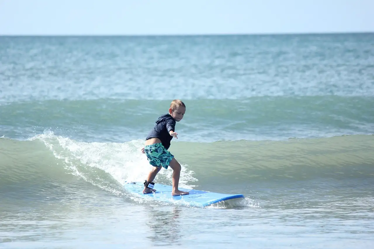 A young surfer riding a small wave on a soft board