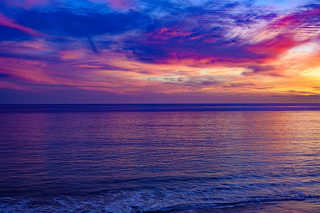 A pink and purple sunset sky over calm water off the Malibu coast