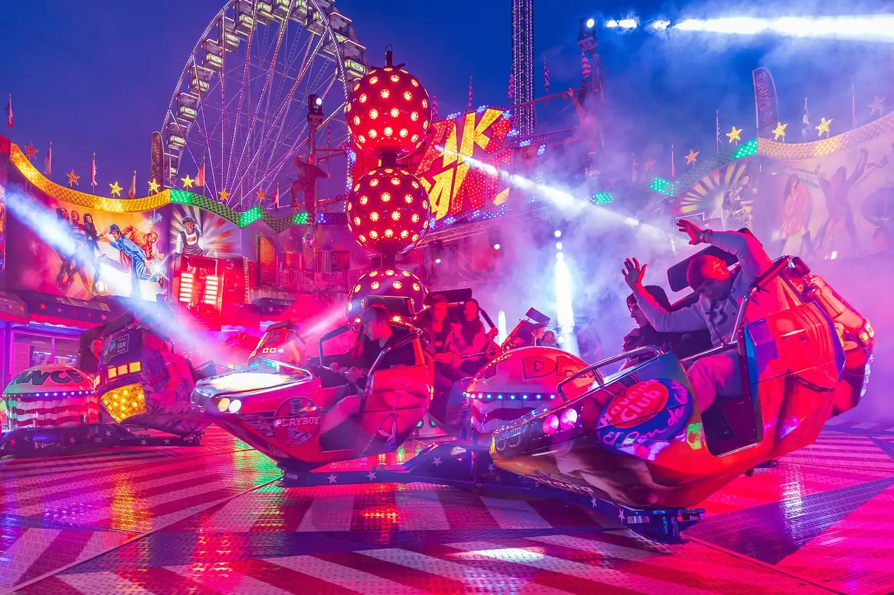 A spinning theme park ride lit up in neon colors at night