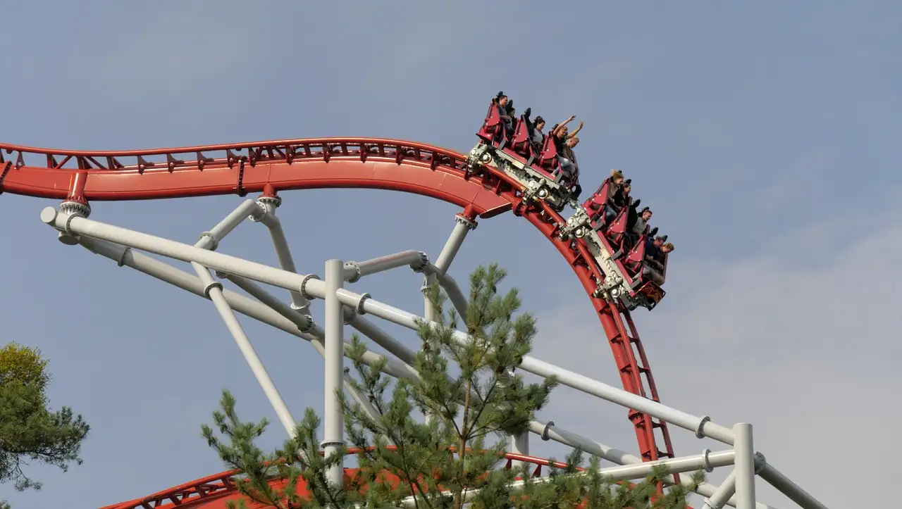 A red roller coaster track curving against a grey sky