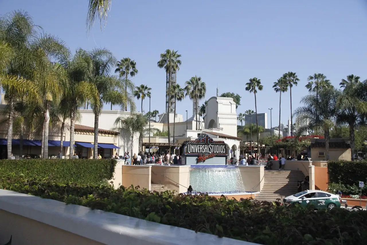 Palm-lined entrance plaza of Universal Studios Hollywood with a fountain and visitors