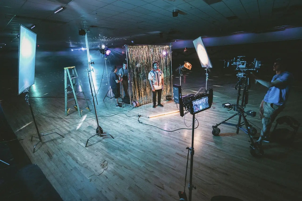 A film crew with cameras and lights setting up a scene on a studio floor